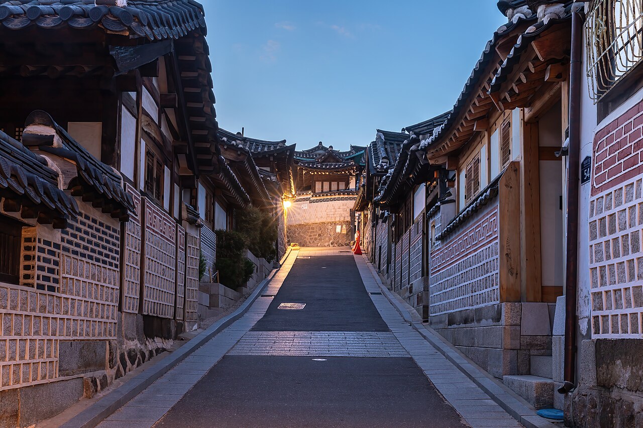 서울 북촌 한옥마을의 푸른 저녁 하늘 아래 따뜻한 가로등이 비추는 한옥 사이 오르막 골목
