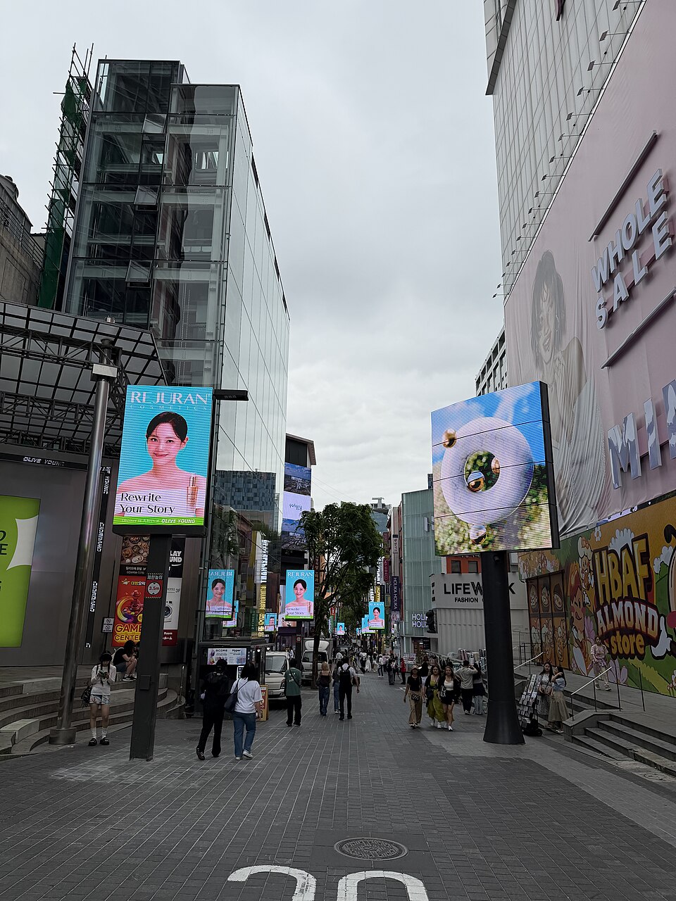 상점과 대형 간판 사이로 사람들이 걷는 명동 쇼핑 거리